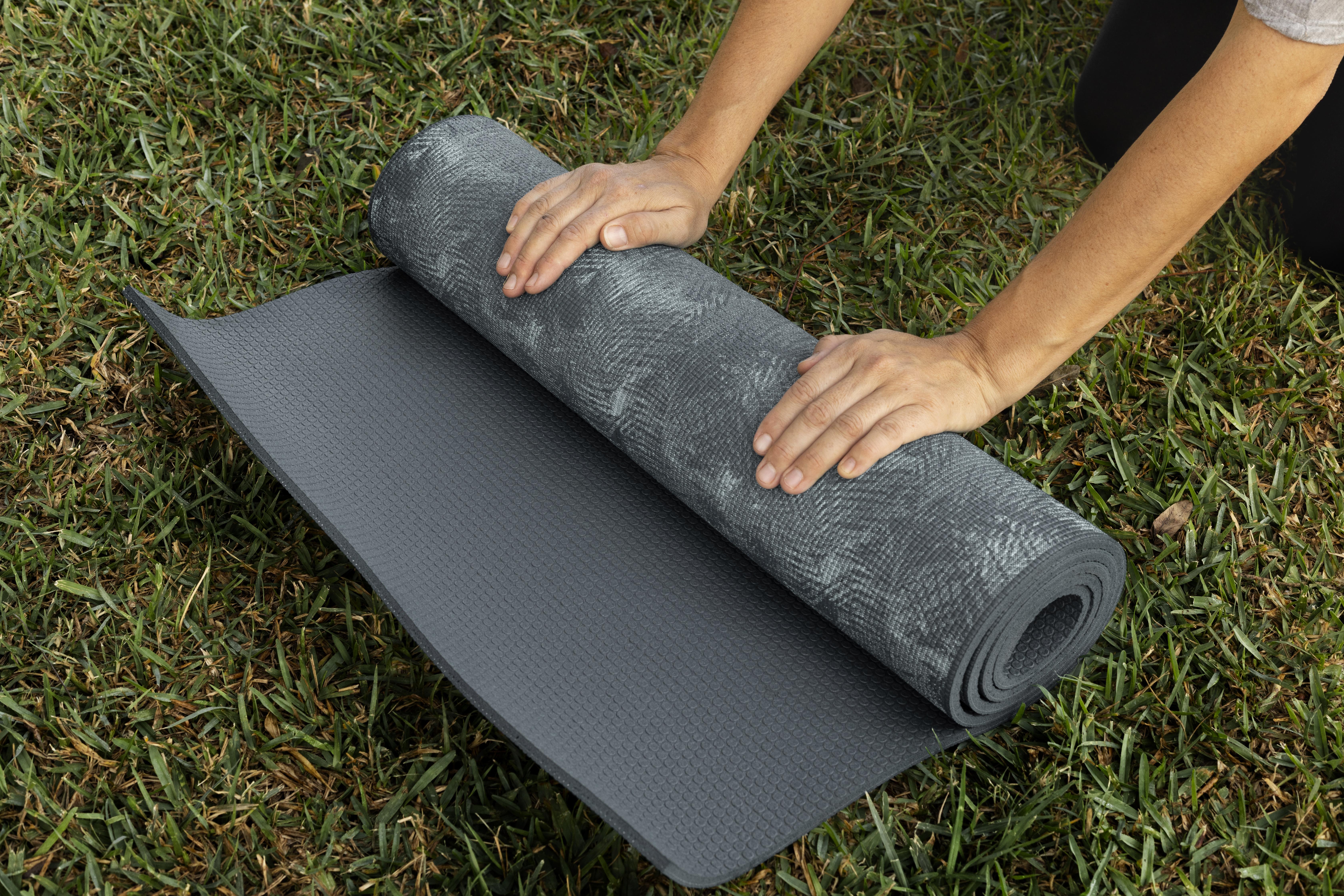 woman-rolling-yoga-mat-grass